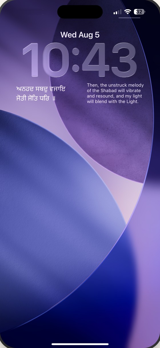 An iPhone Lock Screen carrying a line of Gurbani in Gurmukhi and its English translation beneath the clock.